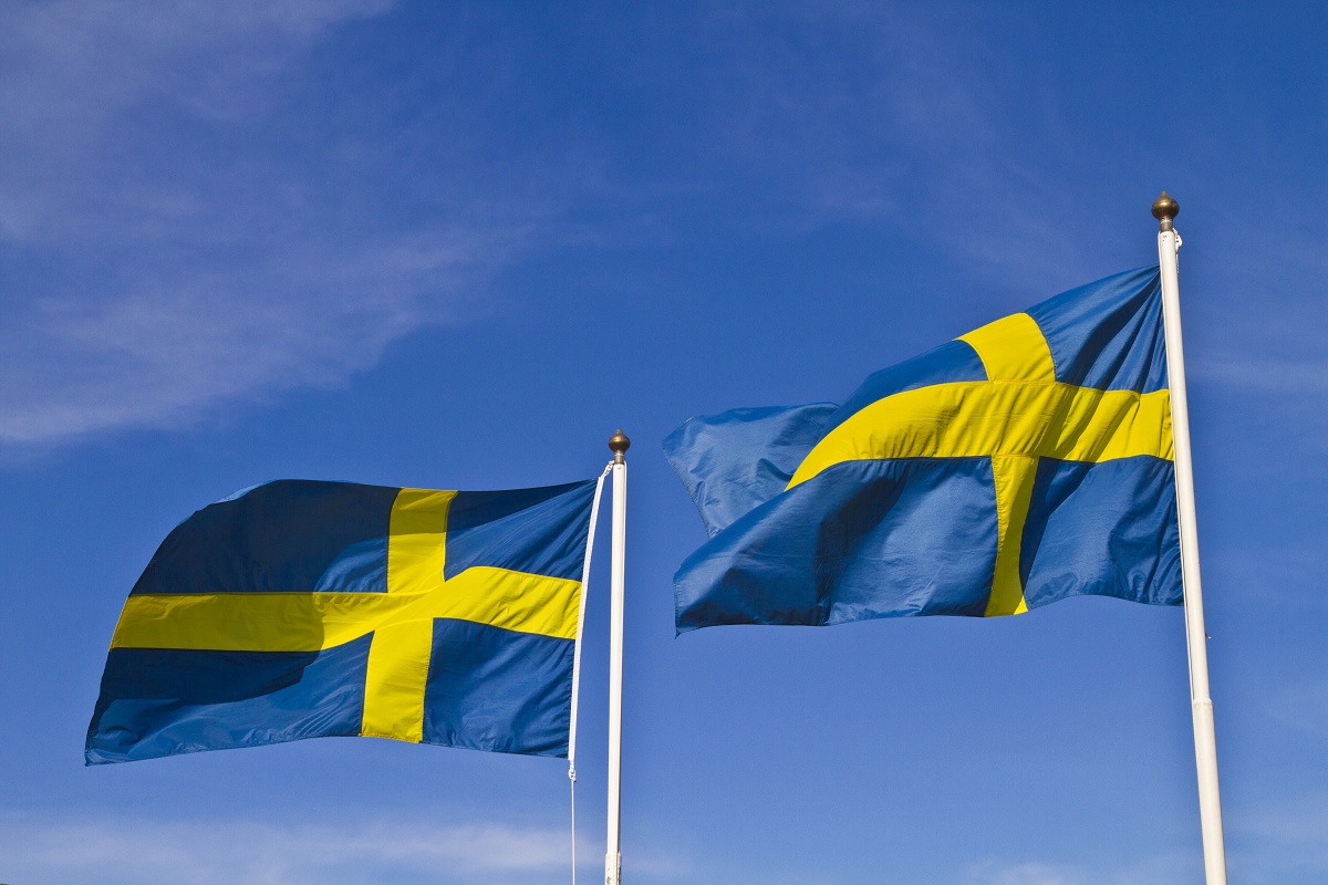 Två svenska flaggor med en blå himmel som bakgrund.