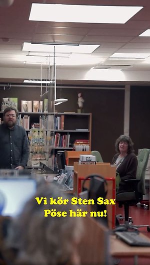 Bild på två personer i ett bibliotek och texten "Vi kör Sten Sax Pöse här nu!". 