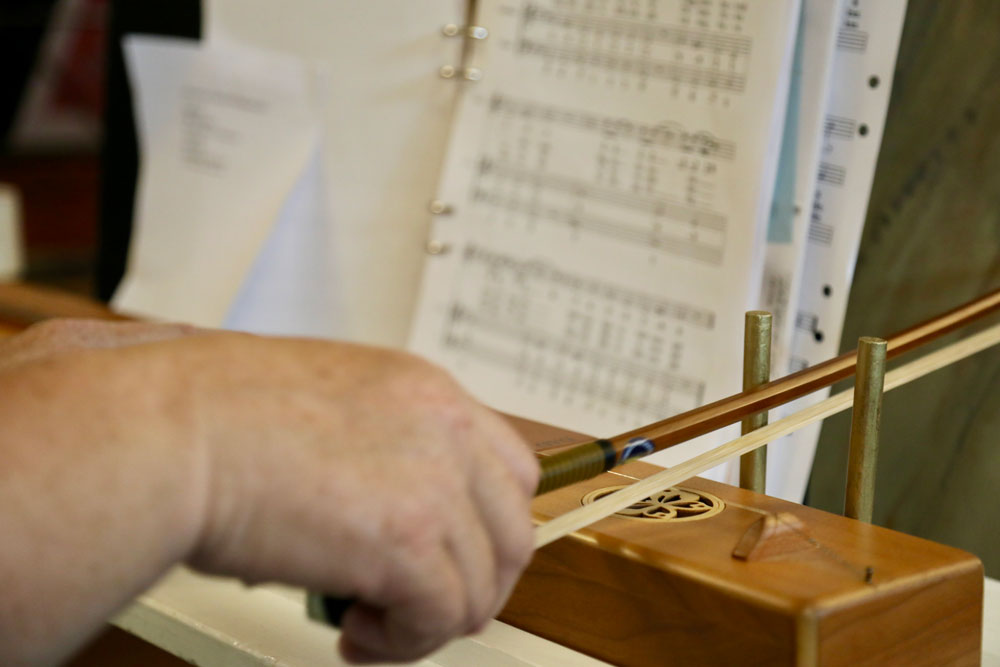 Närbild på hand som spelar psalmodikon med stråke.