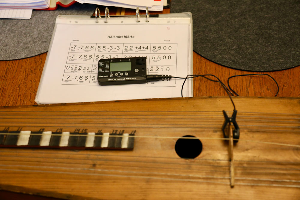 Bild på psalmodikon som ligger på ett bord med noter i sifferform.
