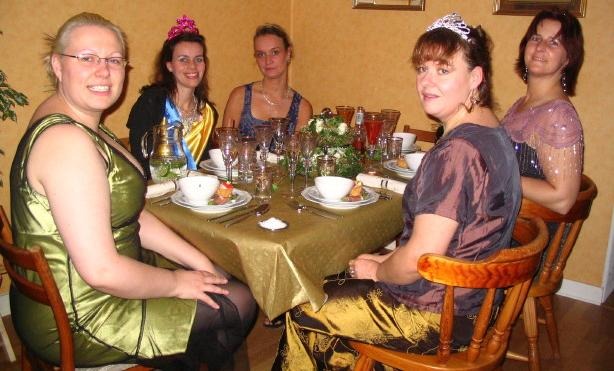 fem uppklädda personer som sitter runt ett festdukat bord