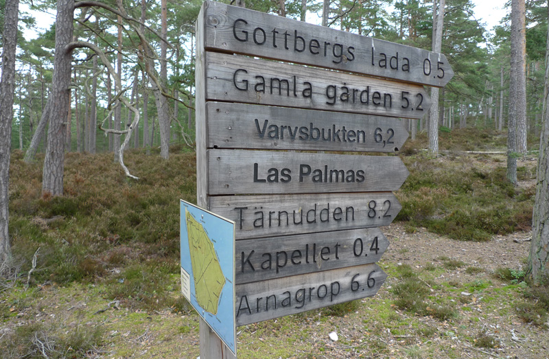 En rad med träskyltar som pekar åt olika håll. Där står "Gottbergs lada 0,5", "Gamla gården 5,2", "Varvsbukten 6,2", "Las Palmas", "Tärnudden 8,2", "Kapellet 0,4" och "Arnagrop 6,6".