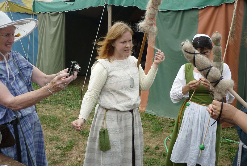 Personer klädda i medeltidskläder spinner. 