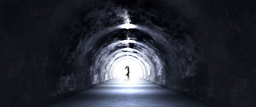 Fotografi föreställande kvinnosilluett som syns i motljus i änden av en tunnel. 