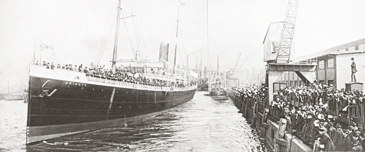 Stort fartyg ankrad vid hamn full med människor.