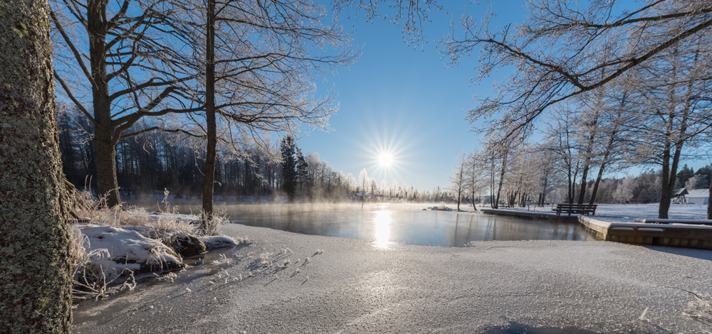 sol lyser på isig sjö