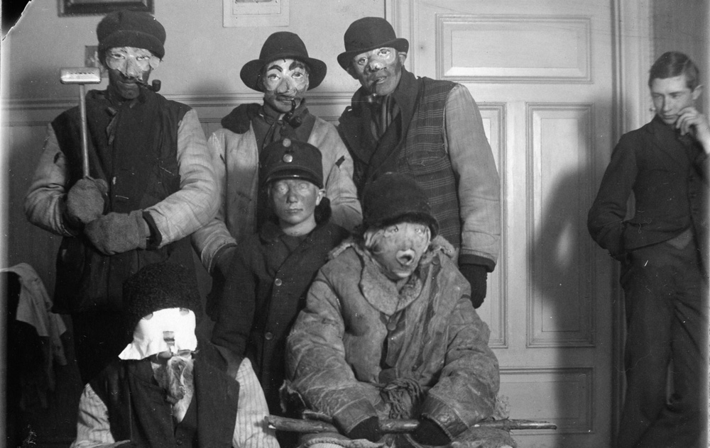 svartvitt fotografi med fem utklädda personer med ansiktsmasker uppställda framför kameran