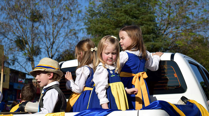 Barn på bilflak klädda i blågula Sverigedräkter.