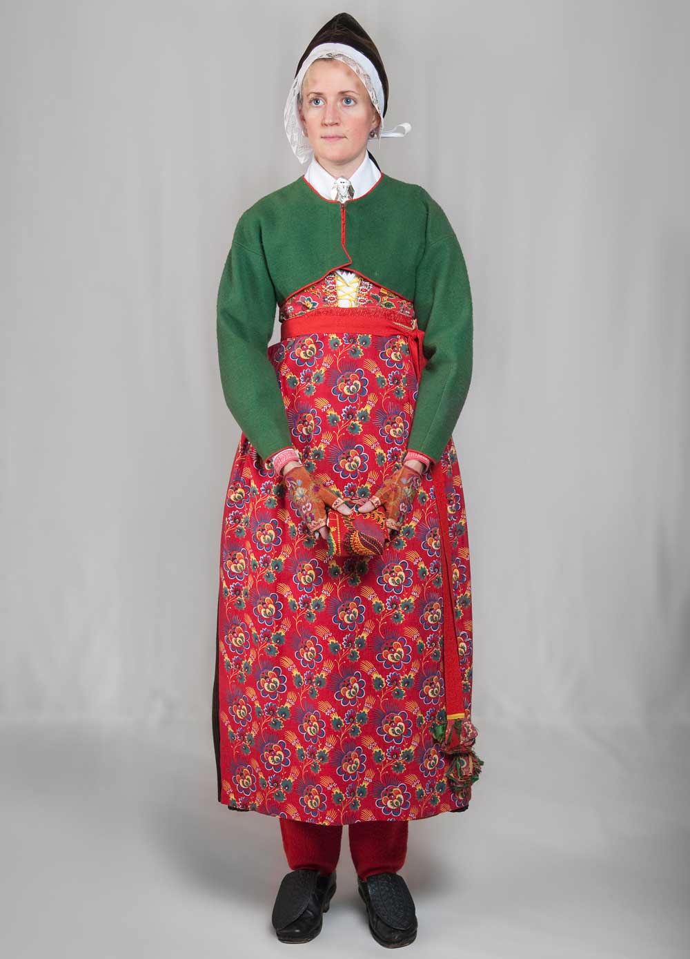Kvinna med rödblommigt förkläde och grön övertröja.