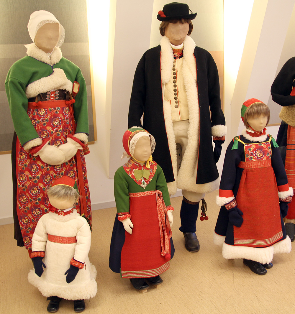 På bilden är det fem dockor, två vuxna och tre barn, alla klädda i folkdräkt