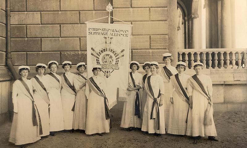 Fotografi av en grupp kvinnor i långa vita klänningar och studentmössor.
