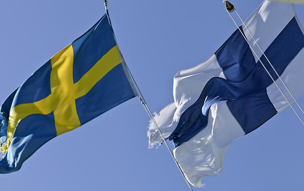 Svensk och finsk flagga som vajar i vinden.