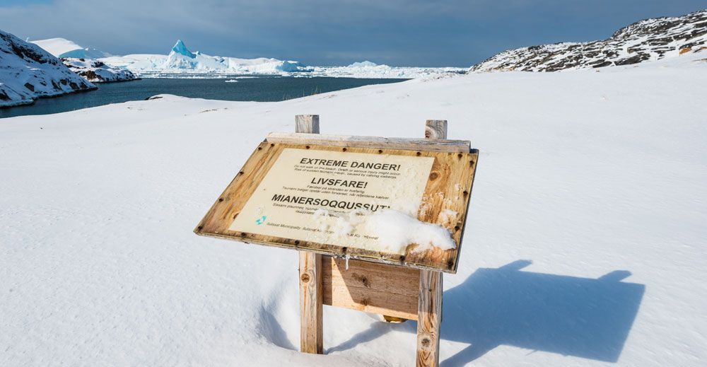 Varningsskylt i glaciärlandskap.