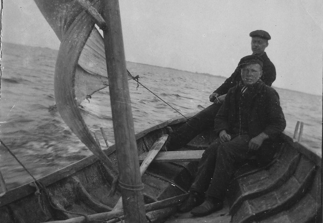 Två män i träbåt med segel.