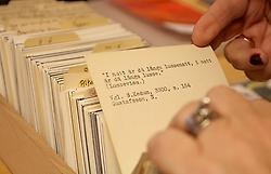 En hand bläddrar genom arkivkort