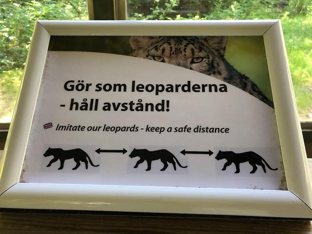 Skylt som visar tre leoparder på rad och har texten "Gör som leoparderna - håll avstånd".