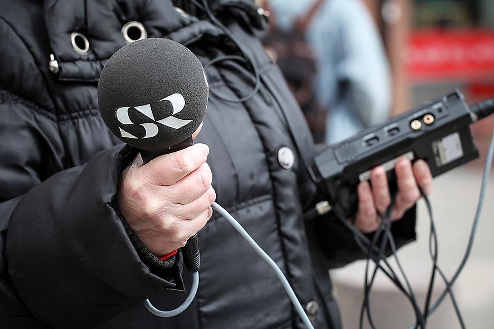 Närbild på inspelningsutrustning och en hand som håller en mikrofon med SR-logga.