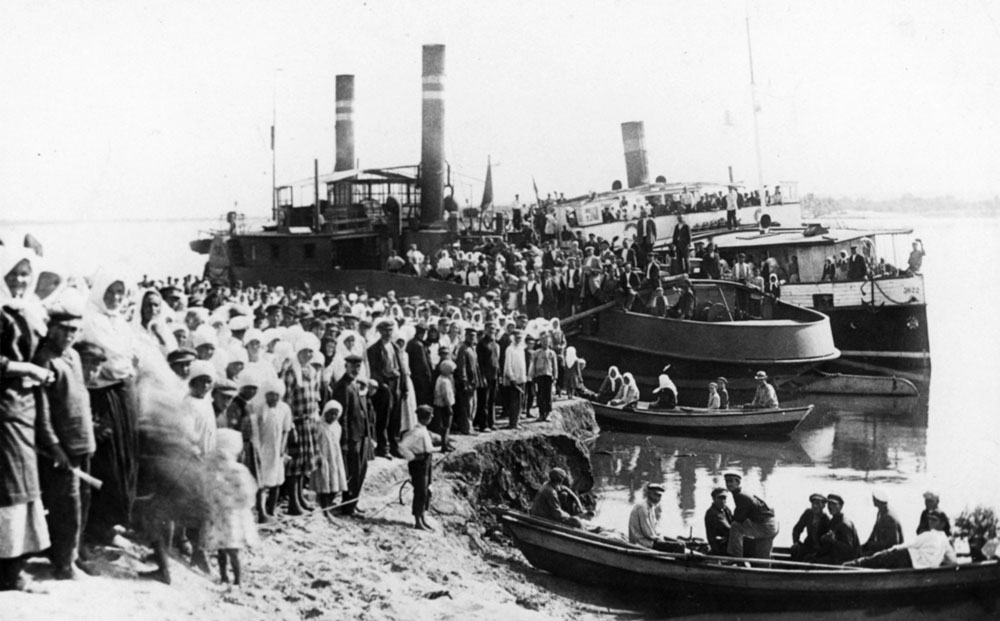 Folksamling i hamn framför stor båt.
