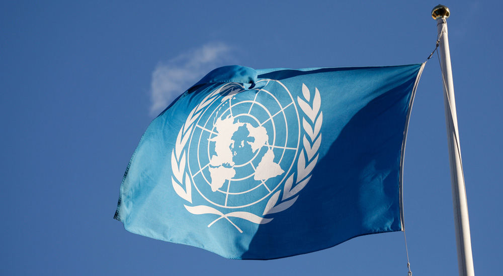 blå FN-flaggan mot klarblå himmel