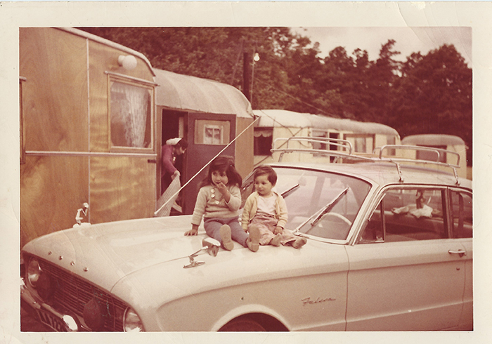 Två barn som sitter på ett biltak.I bakgrunden syns husvagnar.