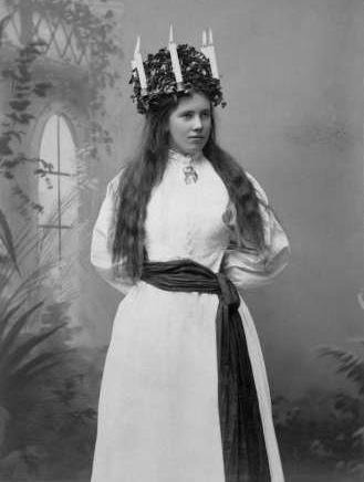 luciaklädd kvinna med utslaget hår och ljuskrona fotograferad i studio
