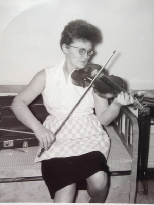 Kvinna sitter ner och spelar fiol.